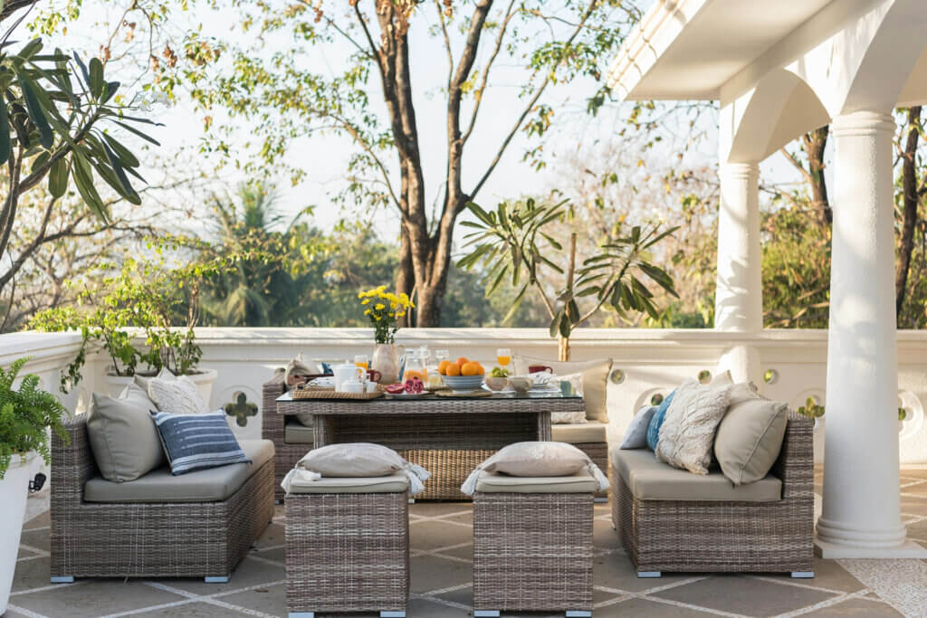 Elegant patio breakfast setup with wicker furniture and tropical garden view