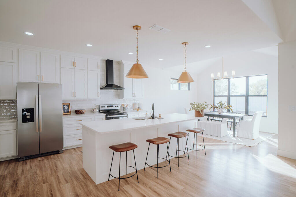 Modern white kitchen with copper pendants and leather barstools