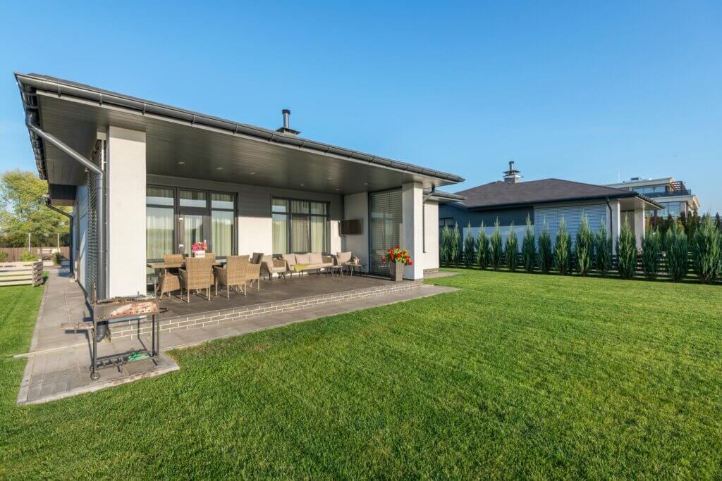 Modern covered patio with wicker furniture and landscaped lawn