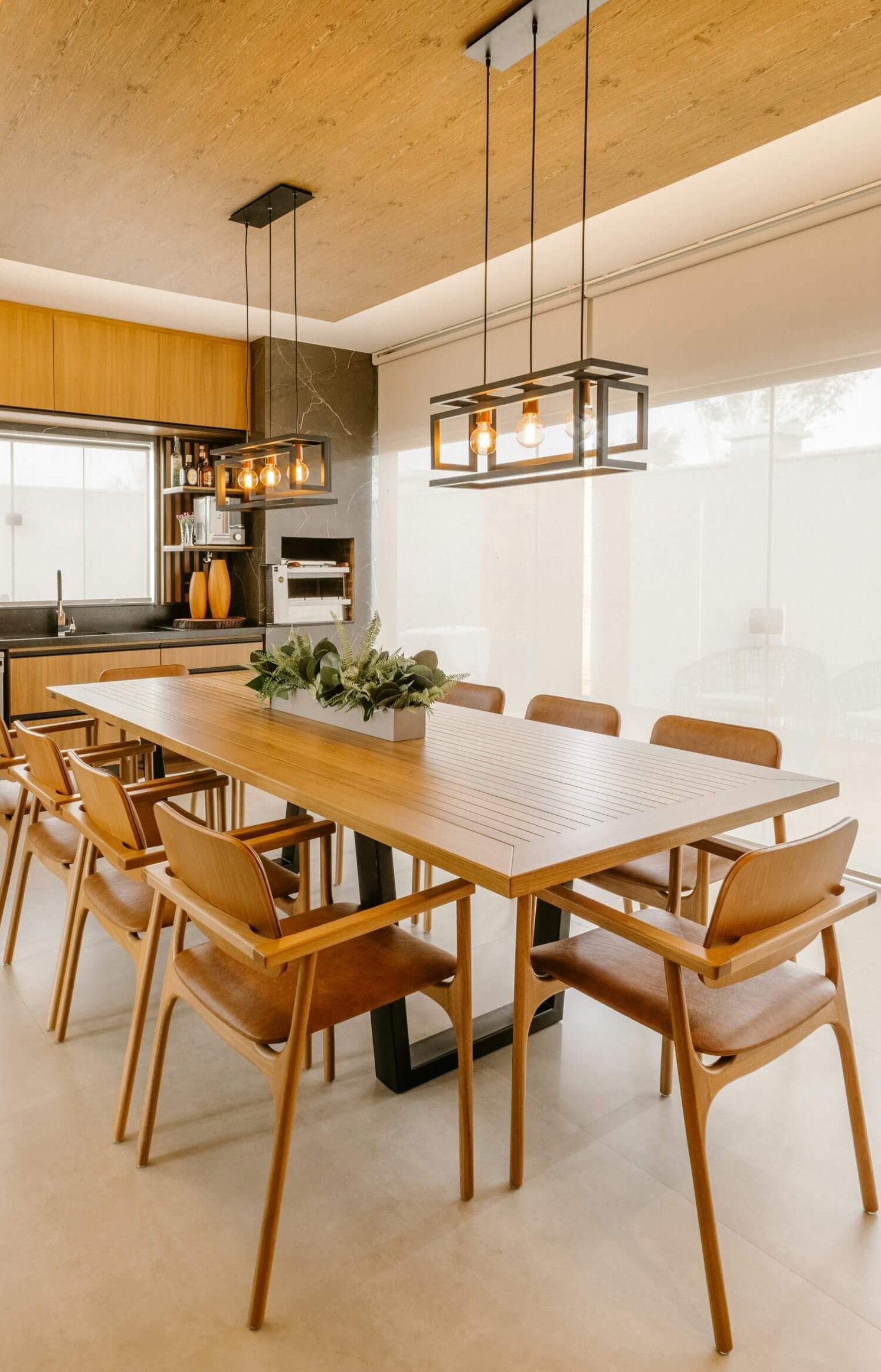 Modern dining room with a wooden table, matching chairs, and pendant lights, creating a cozy ambiance.