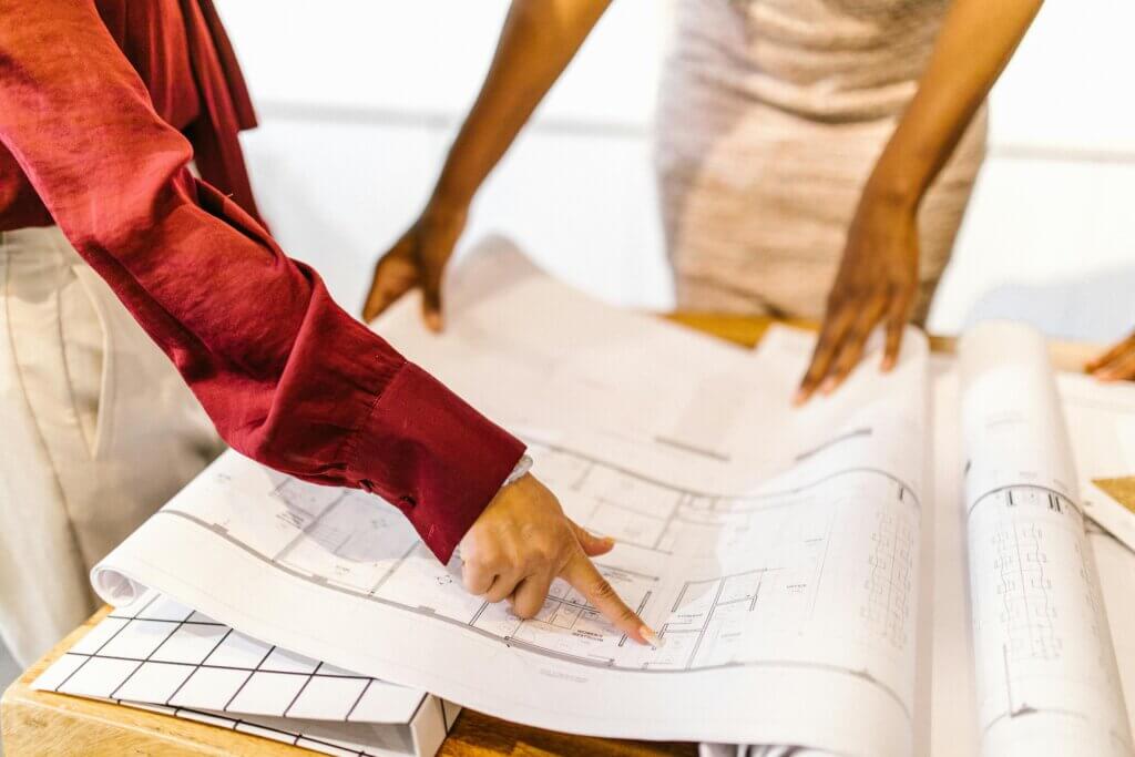 Two people reviewing floor plans on a table, discussing design solutions with wholesale direct furniture.